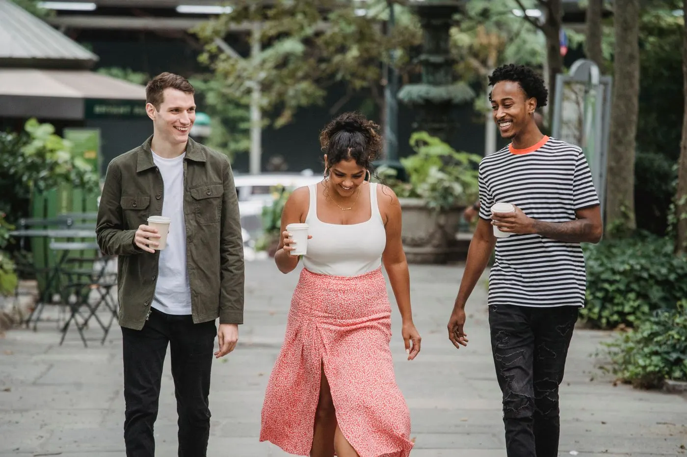 Three diverse friends walking and smiling together outdoors